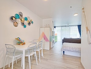 A modern room with a dining area, a bed, and a view of the outdoors. - Studio in Anse Marcel (Saint-Martin)