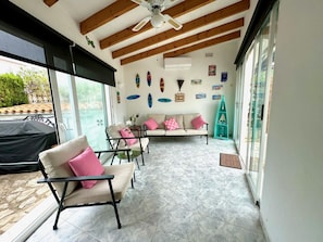 A sunlit patio with a sofa, chairs, and a ceiling fan. - Villa in Els Poblets, Spain (Denia)