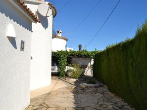 A narrow stone pathway leading to a white building with a tiled roof. - Villa in Els Poblets, Spain (Denia)