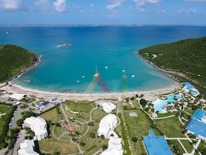 An aerial view of a coastal resort with a beach, swimming pool, and several buildings. - Elegant Suite in Anse Marcel with Air Conditioning and Parking (Saint-Martin)