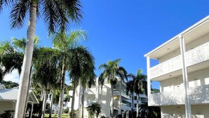 A resort with multiple white buildings, palm trees, and a clear blue sky. - Elegant suite in Anse Marcel with equipped kitchen and parking (Saint-Martin)