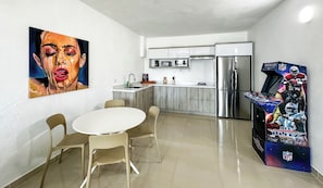 Eine moderne Küche mit Kühlschrank, Mikrowelle und Spüle. Ein Esstisch mit Stühlen und ein Bild an der Wand.