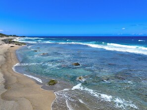 A beach with clear water, rocks, and a sandy shore. - CASSIOPEIA APARTMENT (Hatillo)