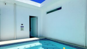 Uma piscina com água azul cristalina, borda azulejada e um aviso na parede com as 'REGRAS DA PISCINA'.