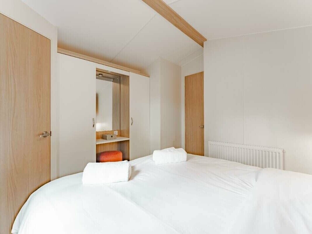 A bedroom with a bed, a wardrobe, and a mirror.