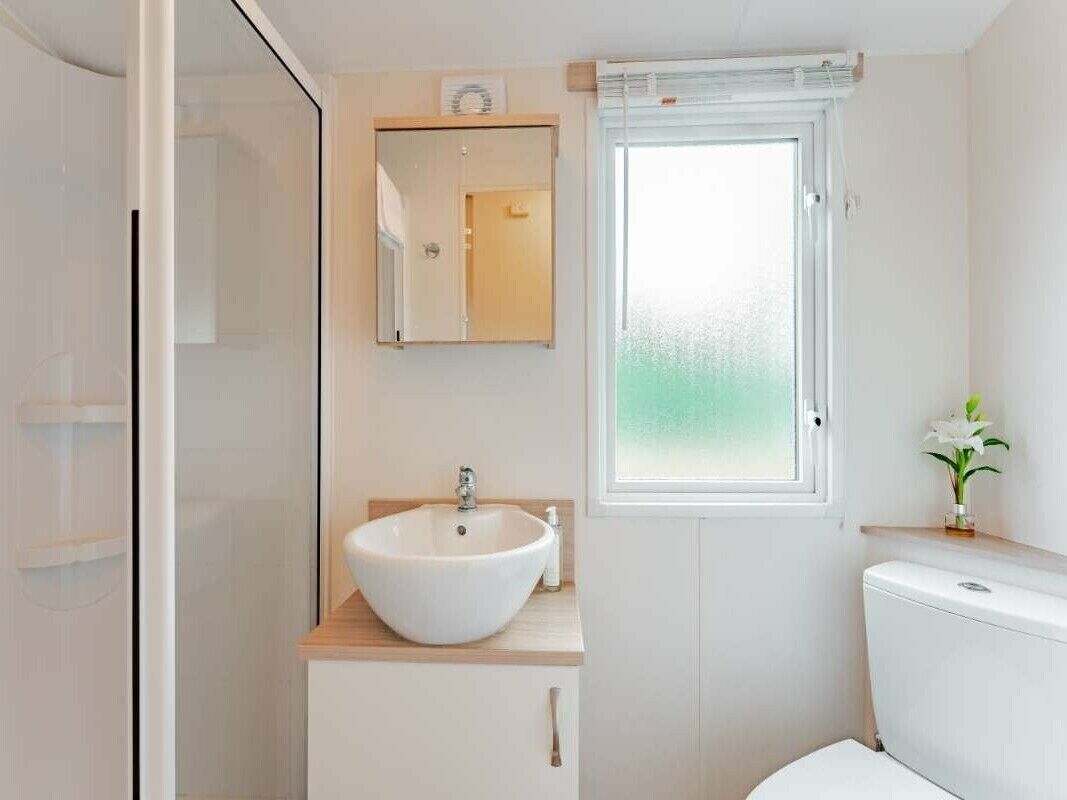 A modern bathroom with a white sink, mirror, and toilet.
