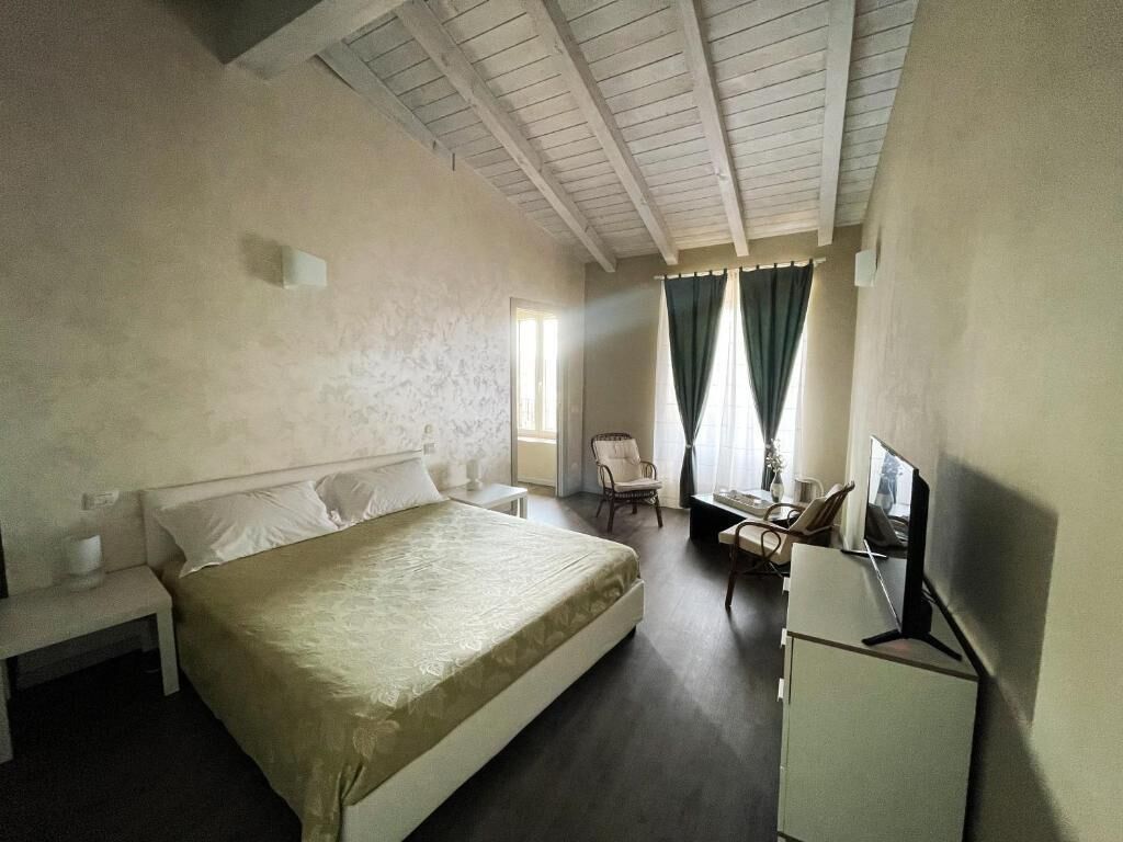 A bedroom with a bed, a desk, a chair, and a television.