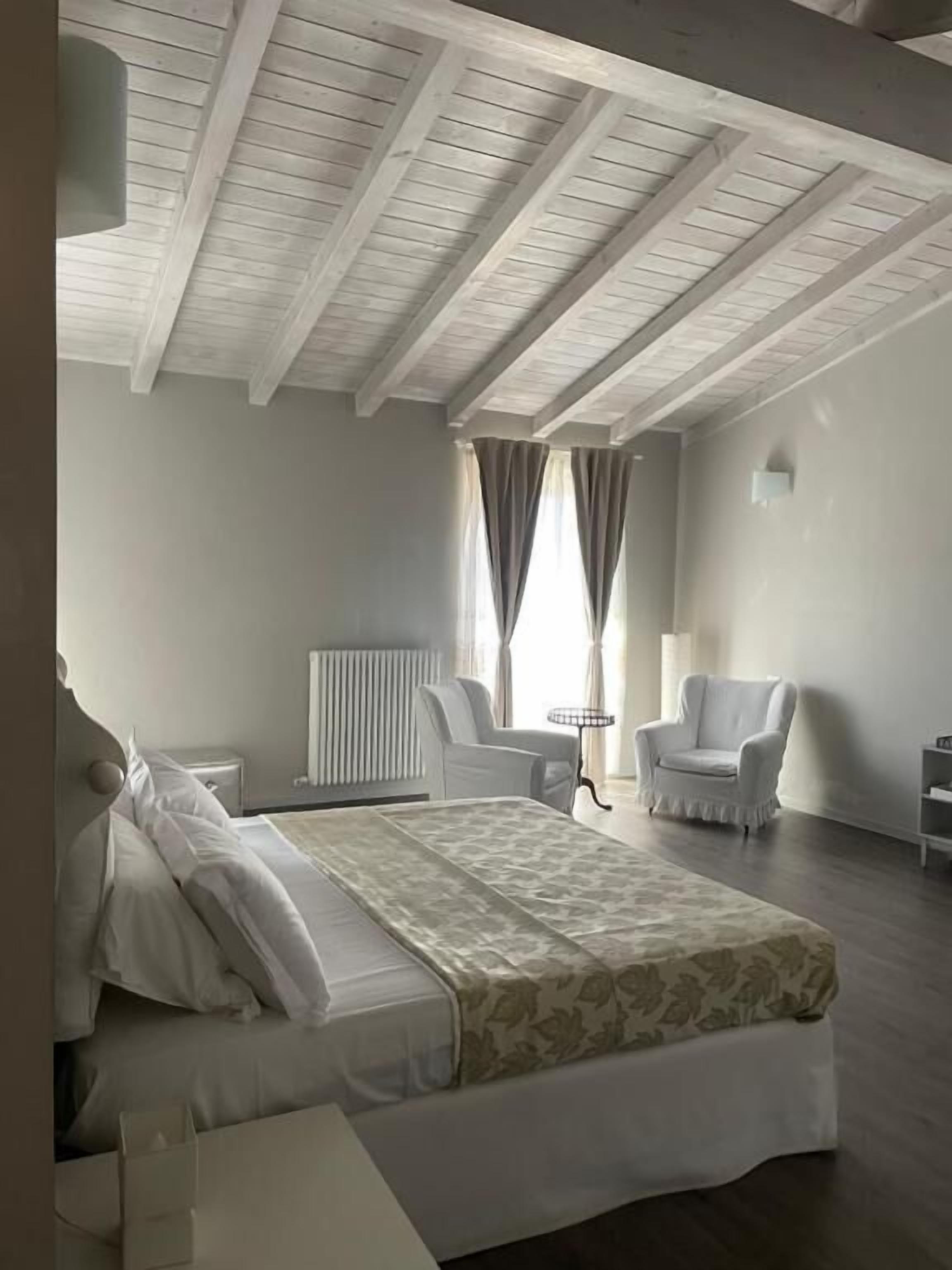 A bedroom with a bed, a chair, a small table, and a radiator.