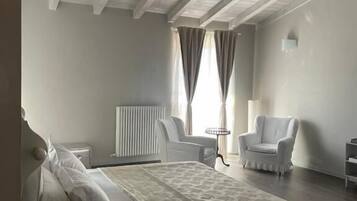 A bedroom with a bed, a chair, a small table, and a radiator.