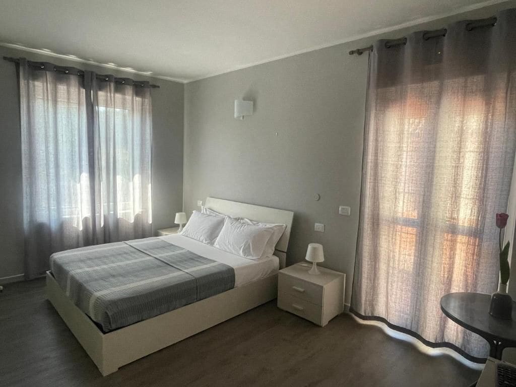 Une chambre à coucher avec un lit, des tables de chevet, une commode et des rideaux.
