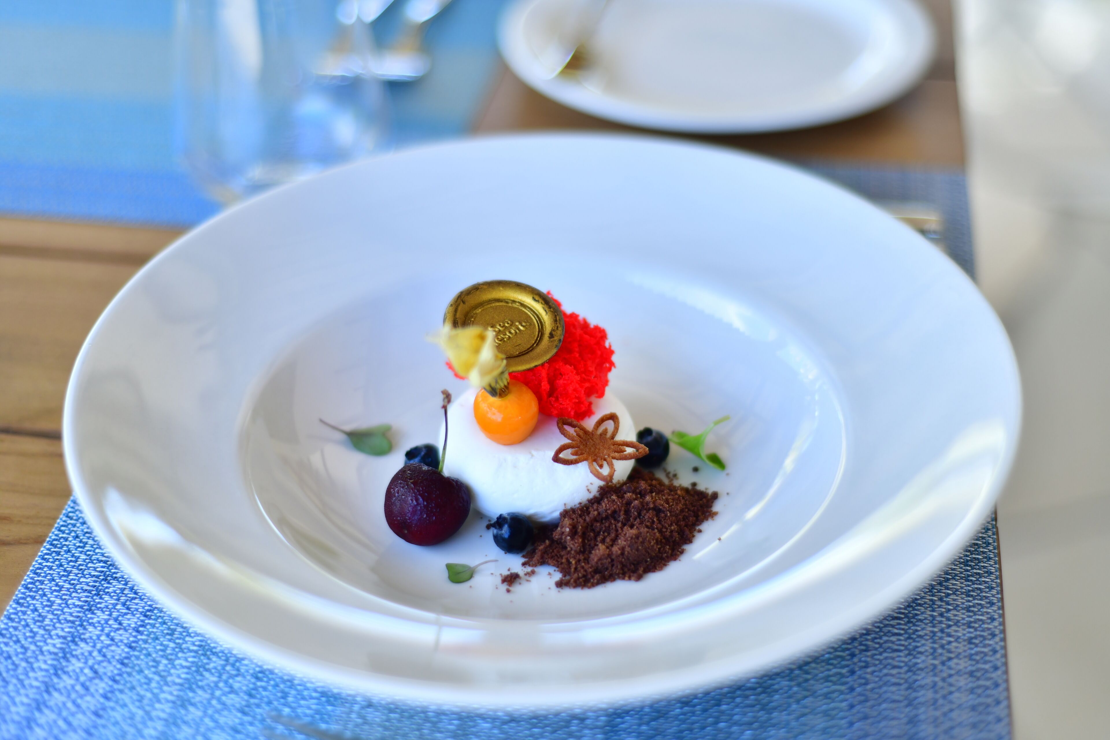 Une assiette blanche avec un dessert, posée sur un set de table bleu.