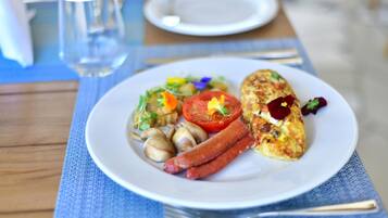 Un plato de comida con varios ingredientes, como tomate, champiñones y salchichas, sobre un plato blanco.