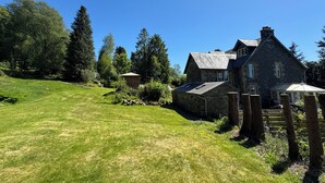 A stone house with a sloped roof, surrounded by a well-maintained lawn and trees. - Crannaig House (Stirling)
