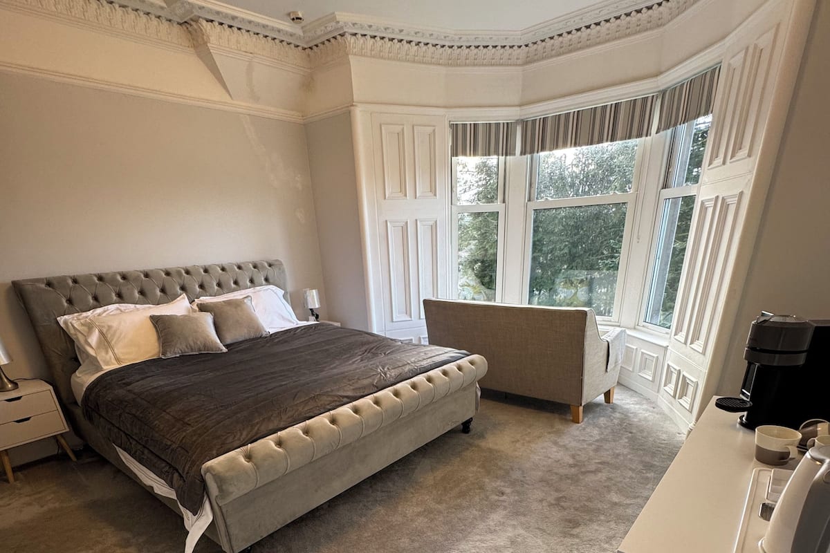 Un dormitorio con una cama grande, una zona de estar y vistas al exterior.