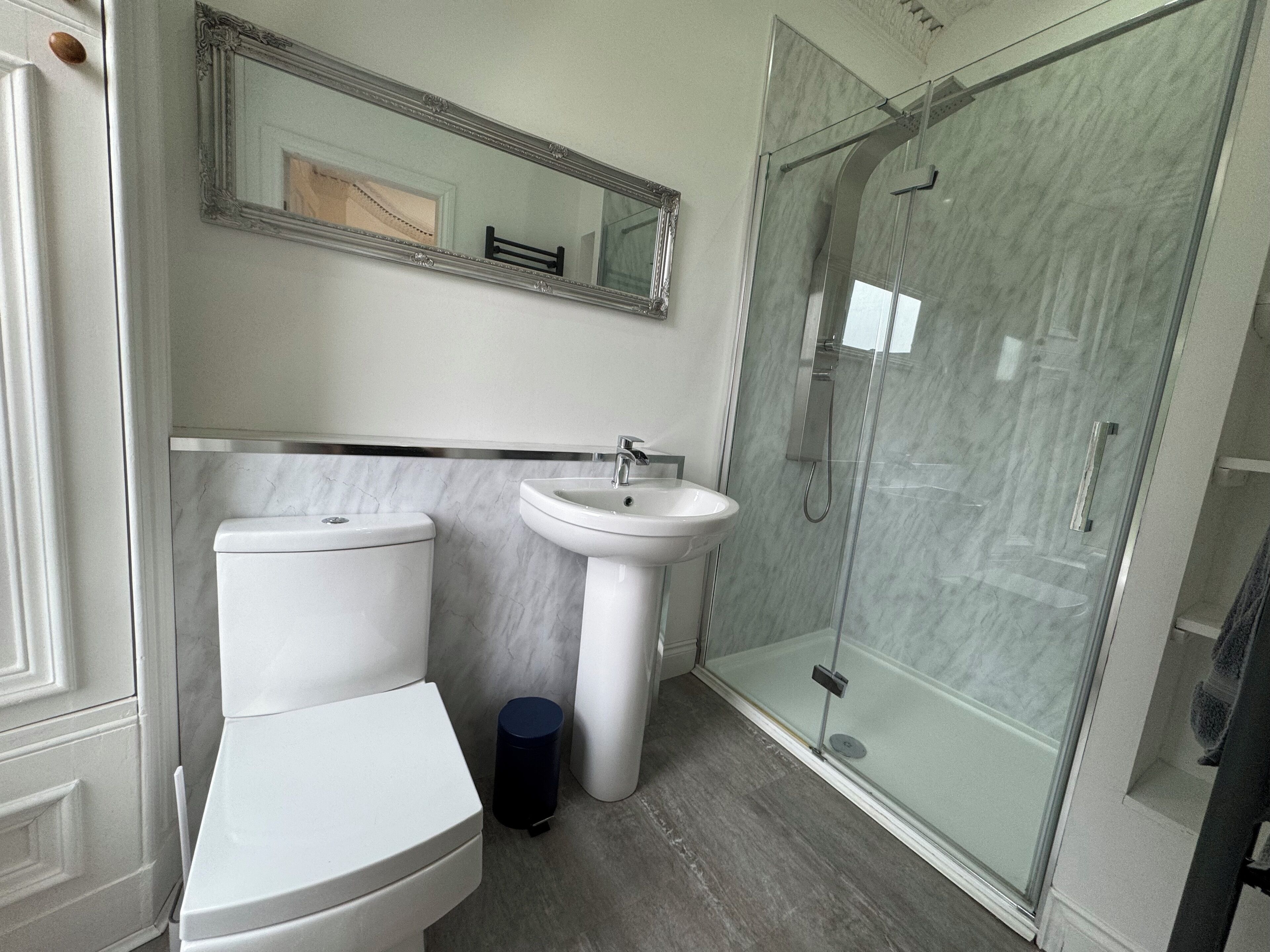 Un bagno moderno con toilette, lavandino e box doccia in vetro.