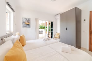 A hotel room with two beds, a large wardrobe, a window with curtains, and a painting on the wall. - Villa Nox is perfect for families with children as the pool is fenced (Albufeira)