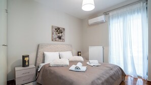 En pænt redt seng med et brunt dynedække og hvide puder, et sengebord med en lampe og et billede på væggen.