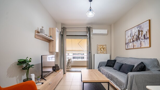En moderne stue med sofa, sofabord, fjernsyn og en plante.