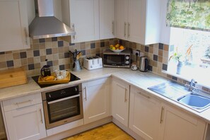 A modern kitchen with white cabinets, stainless steel appliances, a toaster, a microwave, and a sink. - Charming barn Conversion with 2 Bedrooms in beautiful Peak District countryside. Sleeps 4. (Bakewell)