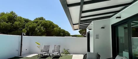 A modern outdoor patio with a swimming pool, lounge chairs, and a covered seating area.