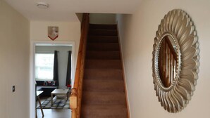 Eine Treppe führt zu einer Zwischenebene, auf der eine dekorative Spiegel an der Wand hängt.