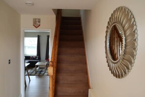 Eine Treppe führt zu einer Zwischenebene, auf der eine dekorative Spiegel an der Wand hängt.