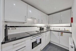 Eine moderne Küche mit weißen Schränken, einer schwarzen Arbeitsplatte und einem eingebauten Backofen.