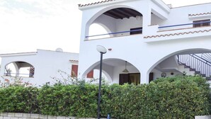 Un bâtiment à deux étages aux murs blancs et aux toits recouverts de tuiles rouges, agrémenté de nombreuses arcades et de balcons.