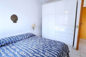 A bedroom with a bed, a wardrobe, and a wall-mounted lamp. - Marina Guest House by Biddizzi Rari - near the beach and veranda with sea view (Sciacca)