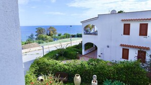 Un bâtiment blanc avec des volets bruns, un balcon et une vue sur la mer.