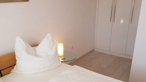 Ett hotellrum med en säng, ett nattduksbord med en lampa och en garderob.