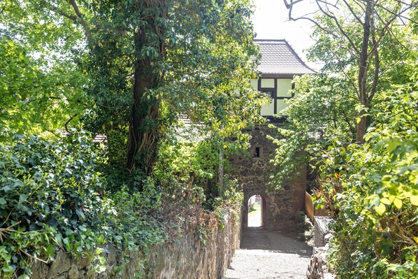 A narrow stone pathway leading to a traditional building with a tiled roof, surrounded by lush greenery. - Apartment 'Fewo50' 2 Bedrooms/2 Bathrooms – No Terrace (Homberg (Efze))
