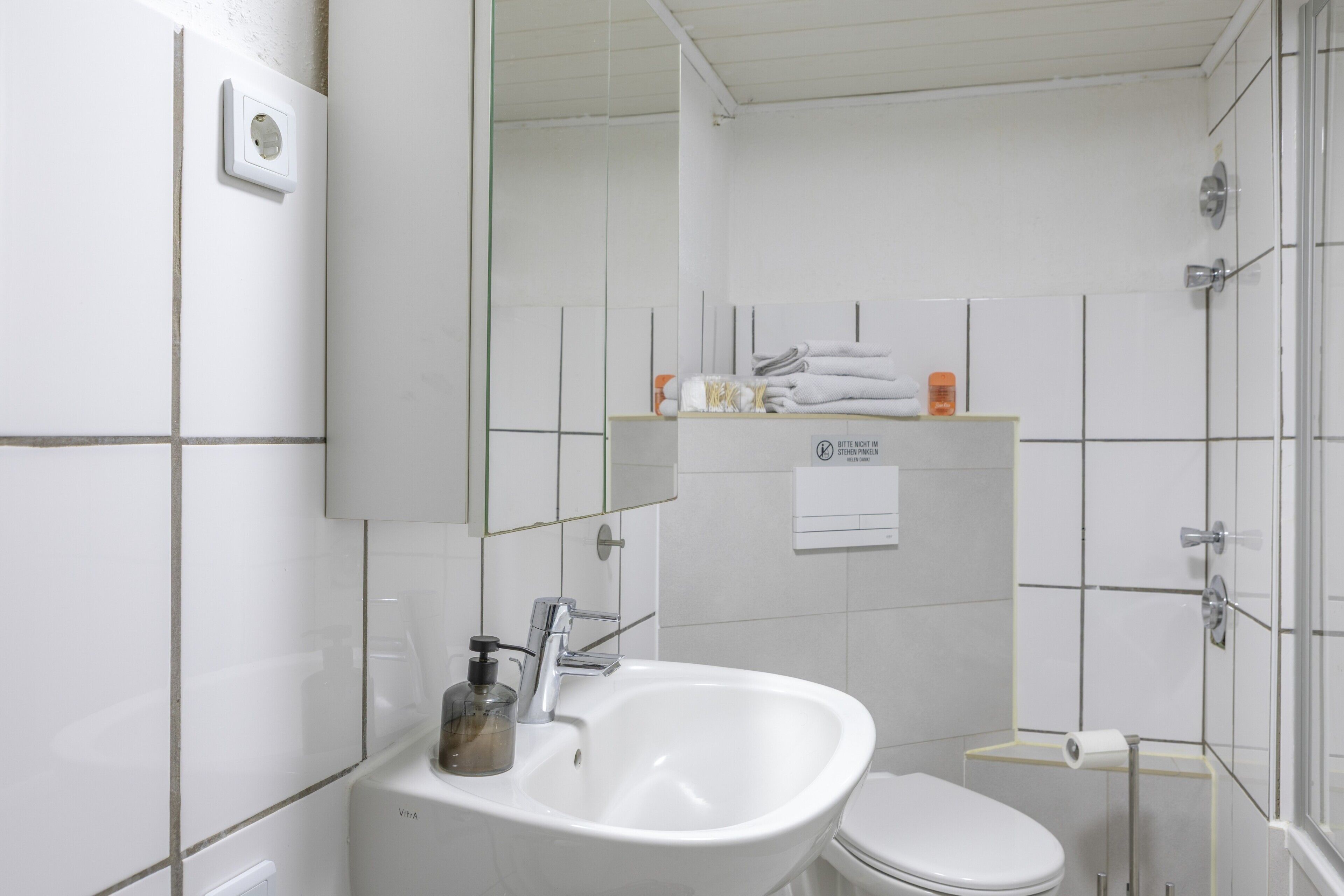 A bathroom with a white sink, toilet, and a mirror above the sink.