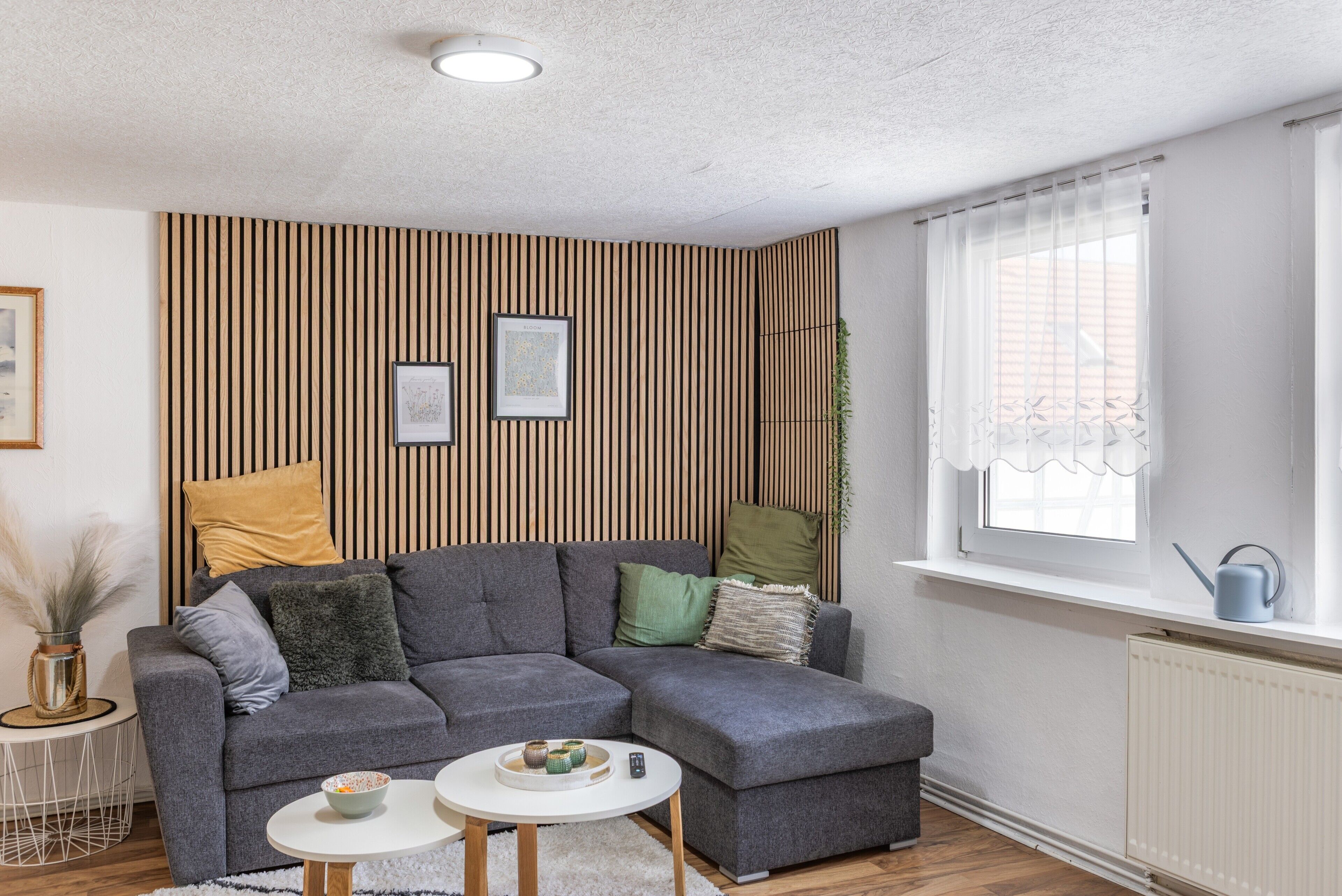 Een moderne woonkamer met een hoekbank, een kleine ronde tafel en een raam met uitzicht.