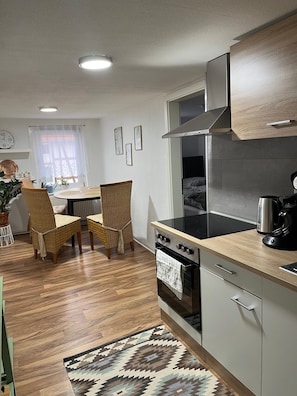 Una cocina moderna con zona de comedor, suelo de madera y alfombra estampada.