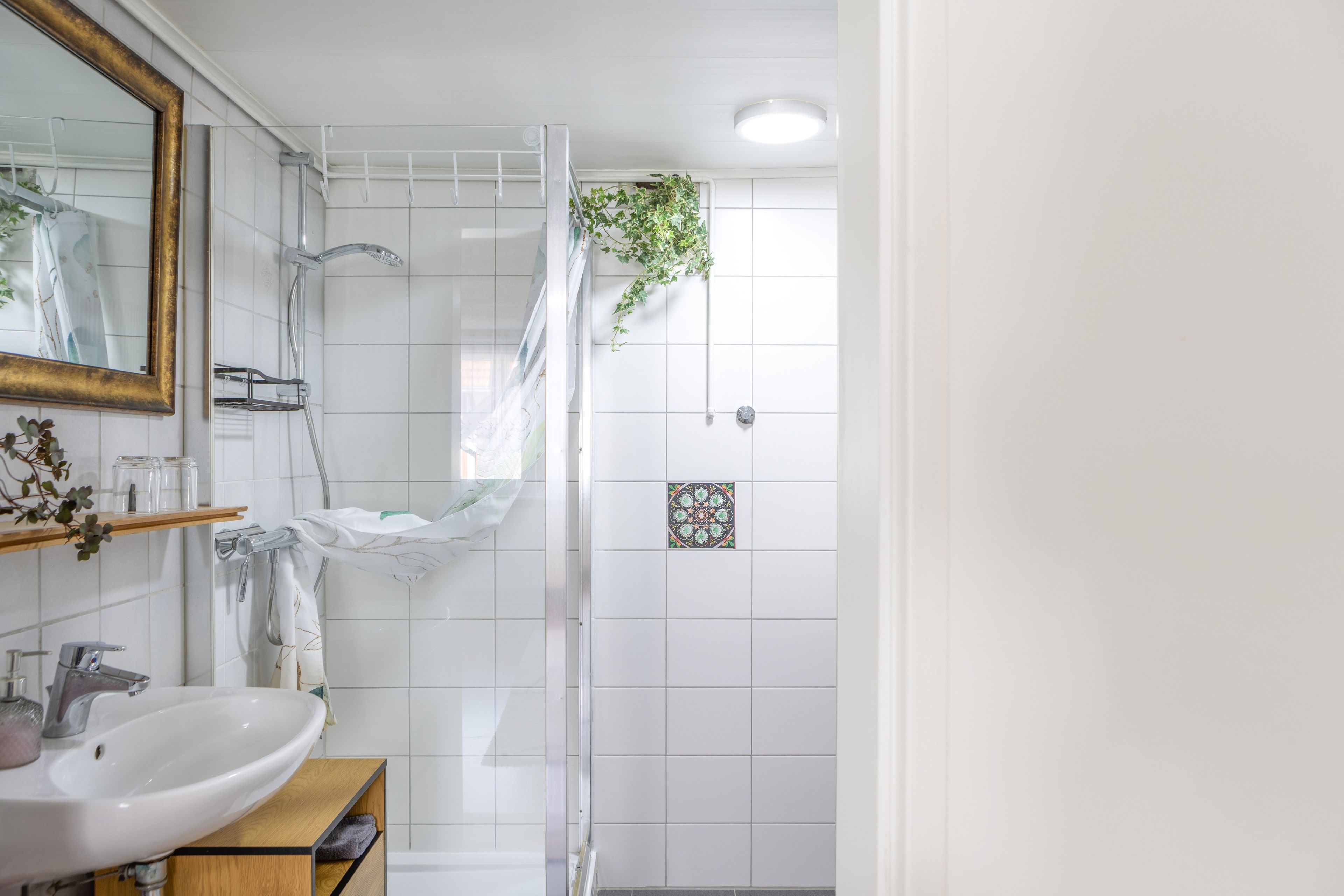 Une salle de bain avec un lavabo blanc, un miroir et une douche.