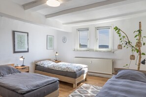 A bedroom with two beds, a window with a view, a wall clock, and a radiator. - Apartment 'Fewo50 - bis 7 Personen, 2 Schlafzimmer/2 Bäder ab 4 Personen' (Homberg (Efze))