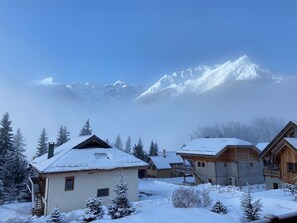 A snow-covered mountain village with wooden houses and a clear view of the snow-capped peaks in the background. - Chalet in Serre Chevalier, Hautes-Alpes, at an elevation of 1,500 meters—Winter and Summer   (Le Monêtier-les-Bains)