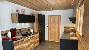 Eine moderne Küche mit Holzschnitzereien, einer zentralen Kochinsel und einem eingebauten Ofen.