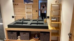 Ein Badezimmer mit einem großen Waschbecken, Holzregalen und einem Spiegel.