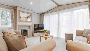 A modern living room with a fireplace, a television, and comfortable seating. - Bella's Retreat - Kelling Heath Holiday Park - 19669 (Holt)
