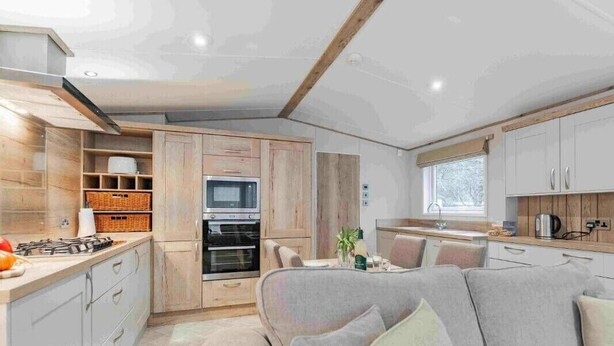 A compact kitchen with wooden cabinets, a built-in oven, and a gas stove. - Bella's Retreat - Kelling Heath Holiday Park - 19669 (Holt)