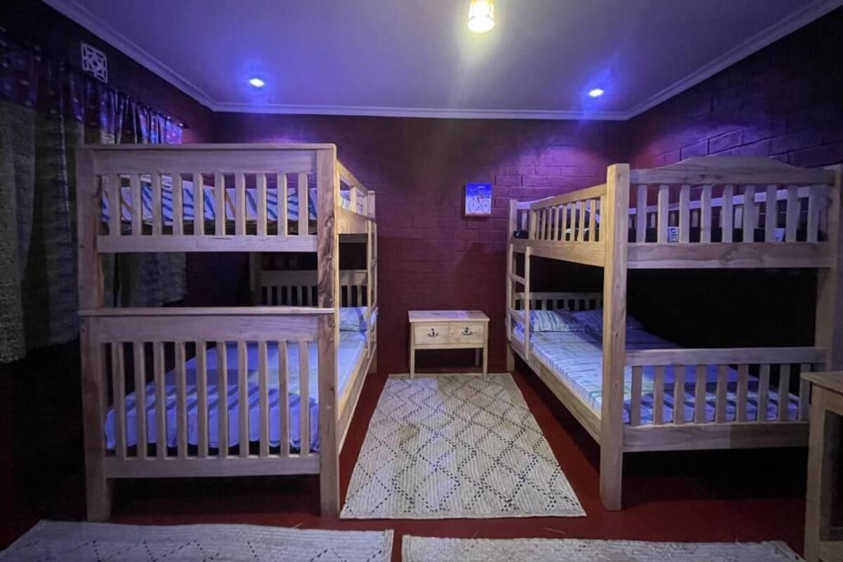 A room with three bunk beds, a small table, and a patterned rug.