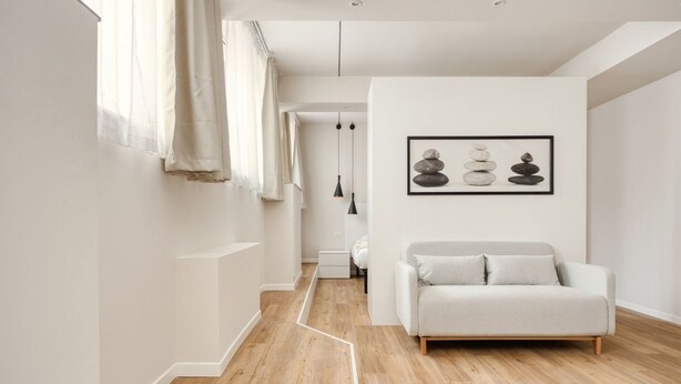 A modern interior with a sofa, a framed artwork, and a wooden floor. - Hostmate - Milano - Imperia's Warm - Romolo IULM (Milano)