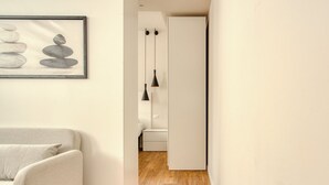 A hallway with a white sofa, a framed artwork of stacked stones, and a wooden floor. - Hostmate - Milano - Imperia's Warm - Romolo IULM (Milano)