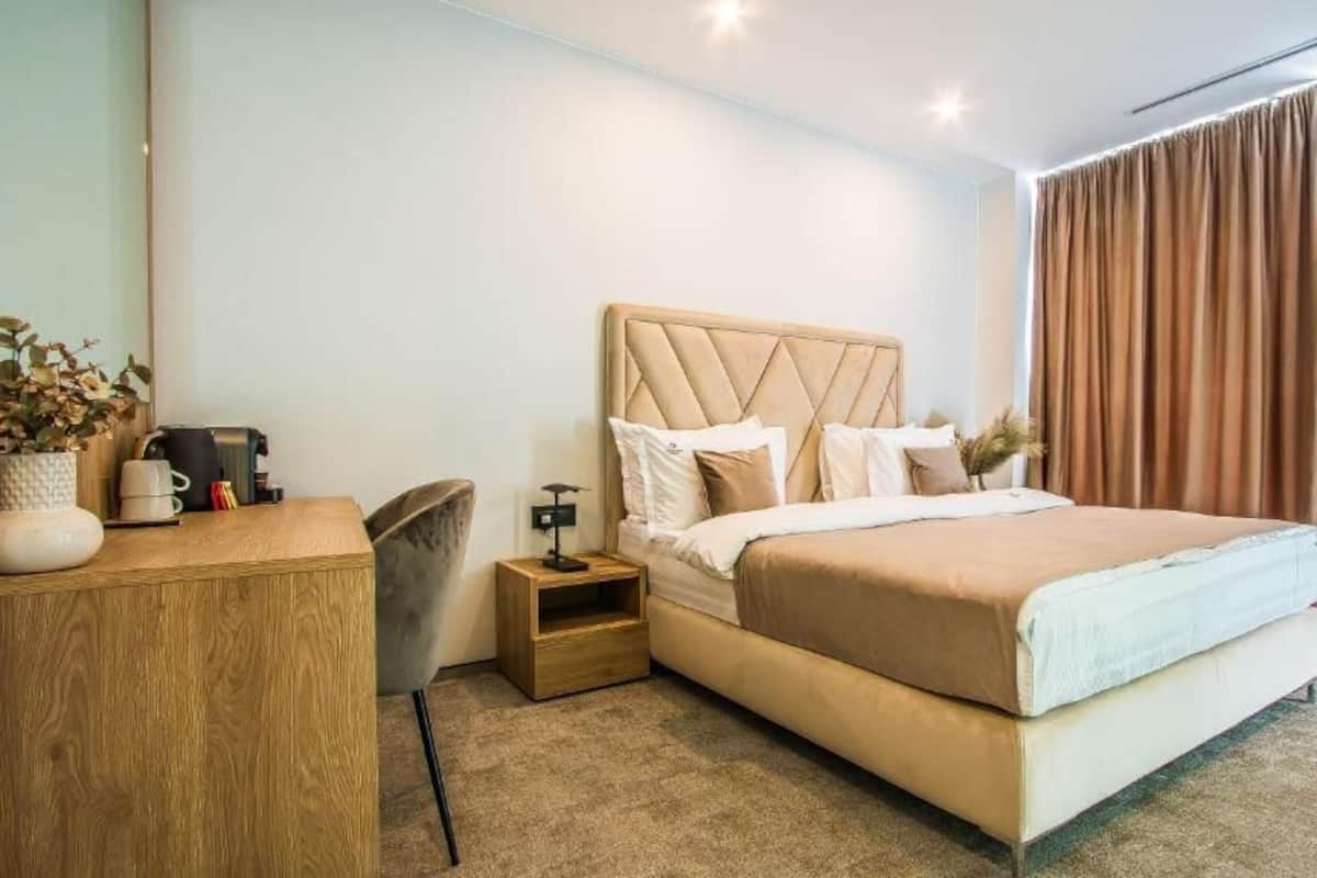 Un dormitorio con cama, mesita de noche, lámpara y escritorio con silla.