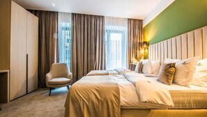 A hotel room with a large bed, a chair, and a wardrobe. - Central Carol APARTHOTEL (Bucharest)