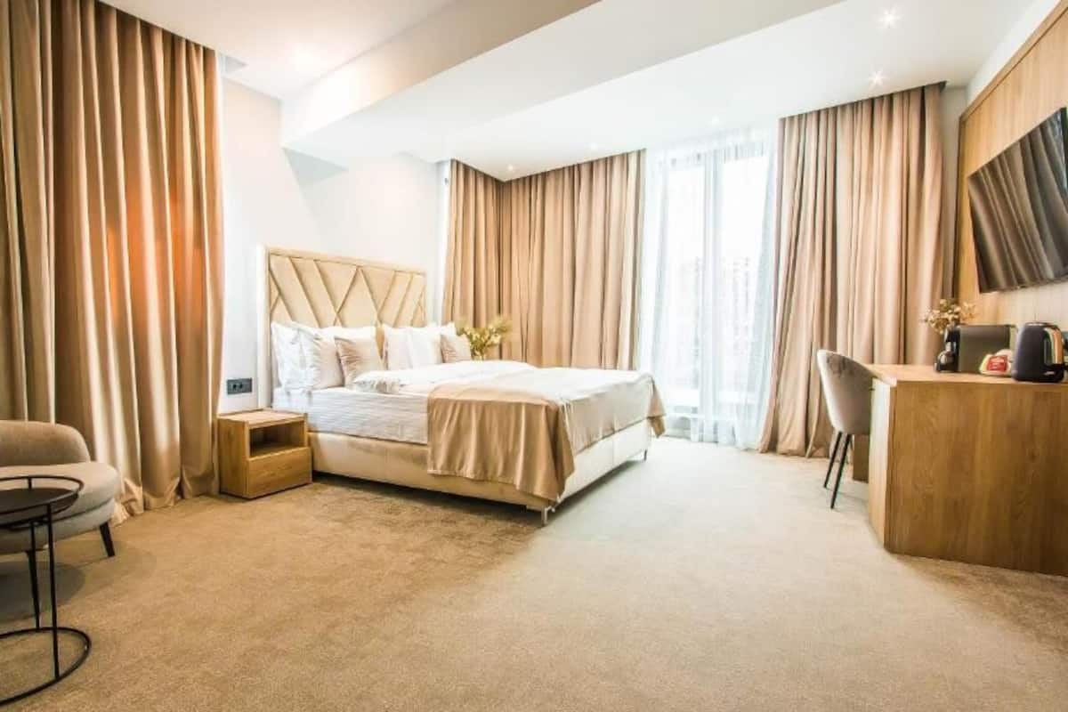 Una habitación de hotel con cama, escritorio, silla y una pequeña mesa.