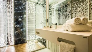 A modern bathroom with a glass partition, a wooden floor, and a stack of towels on the counter. - Central Carol APARTHOTEL (Bucharest)