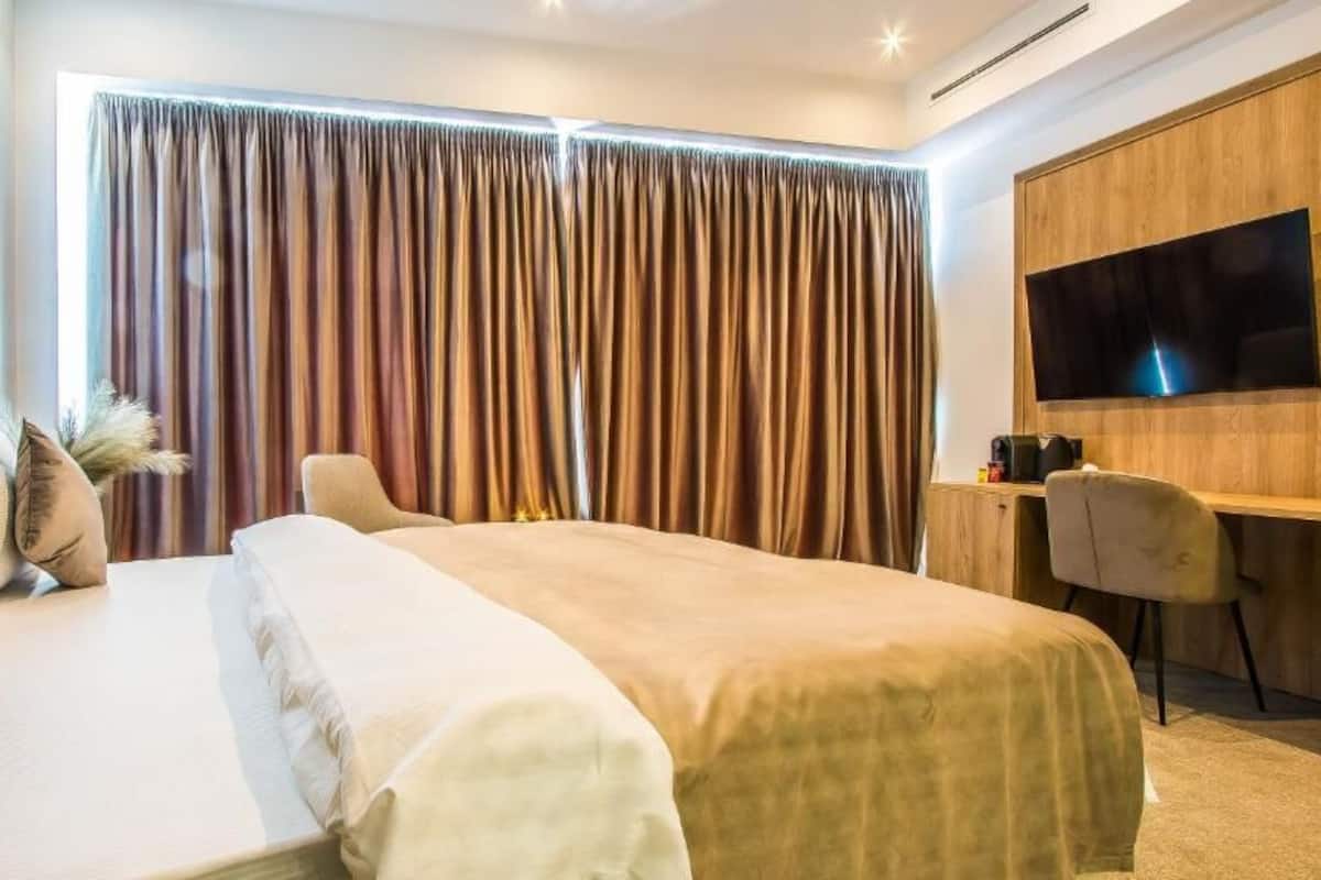 Una habitación de hotel moderna con una cama grande, un escritorio y un televisor en la pared.
